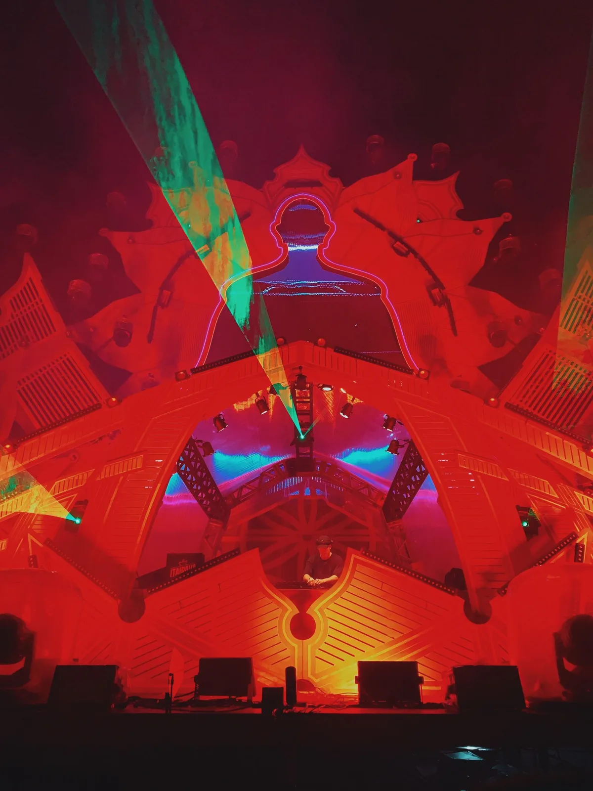 Structure scénique rouge traversée de lasers